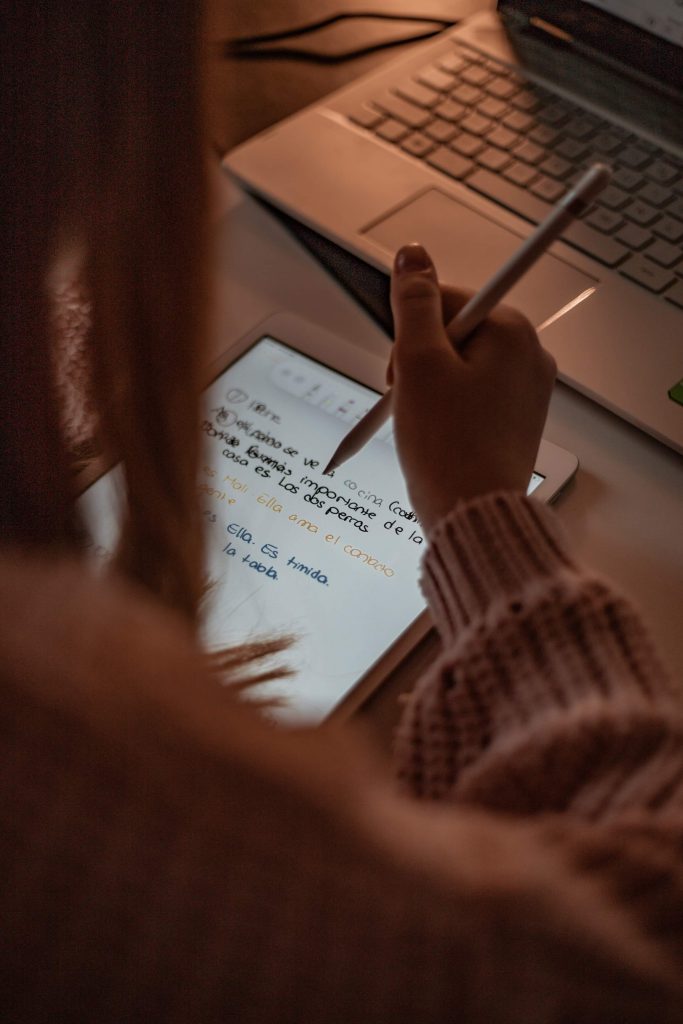 woman writing on ipad